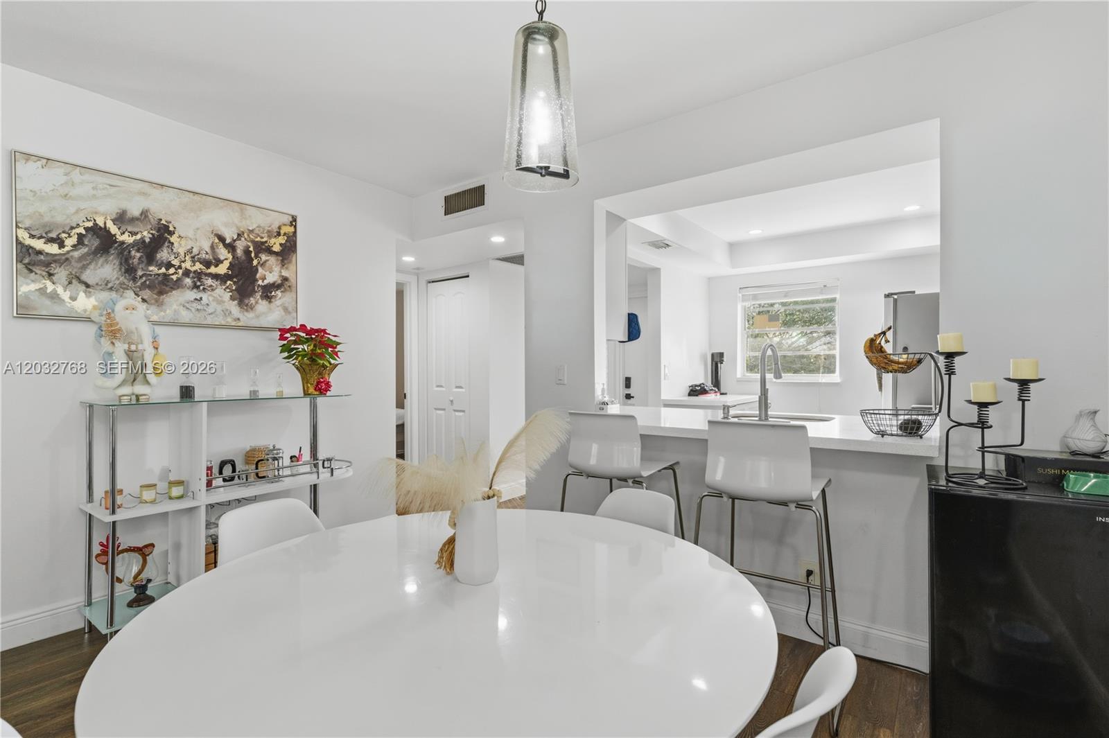 A dining area with a round white table sits adjacent to a kitchen breakfast bar — 9340 Lagoon Pl # 304, Davie FL 33324, DAVIE, FL