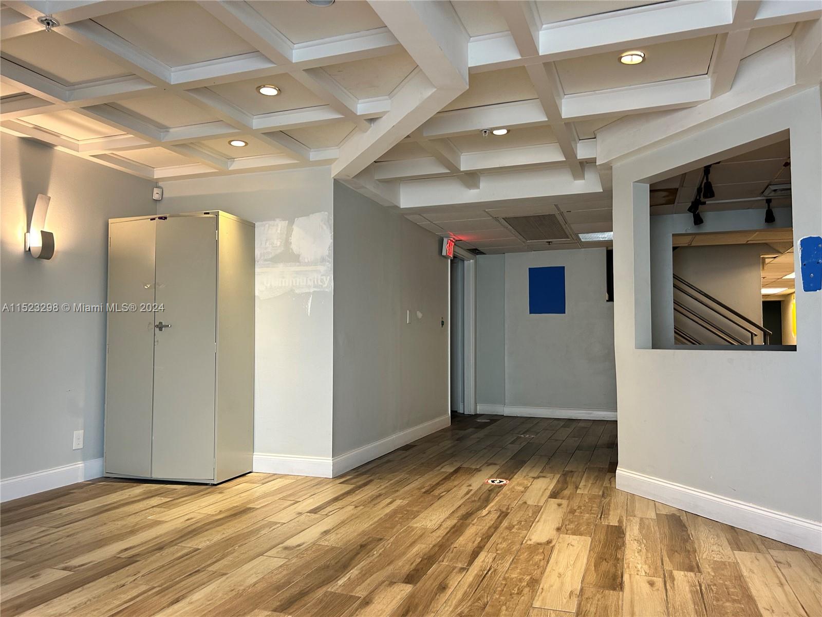 A room with wood-look flooring, a coffered ceiling, and a metal storage cabinet — 2055 Liberty St, Hollywood FL 33020, HOLLYWOOD, FL