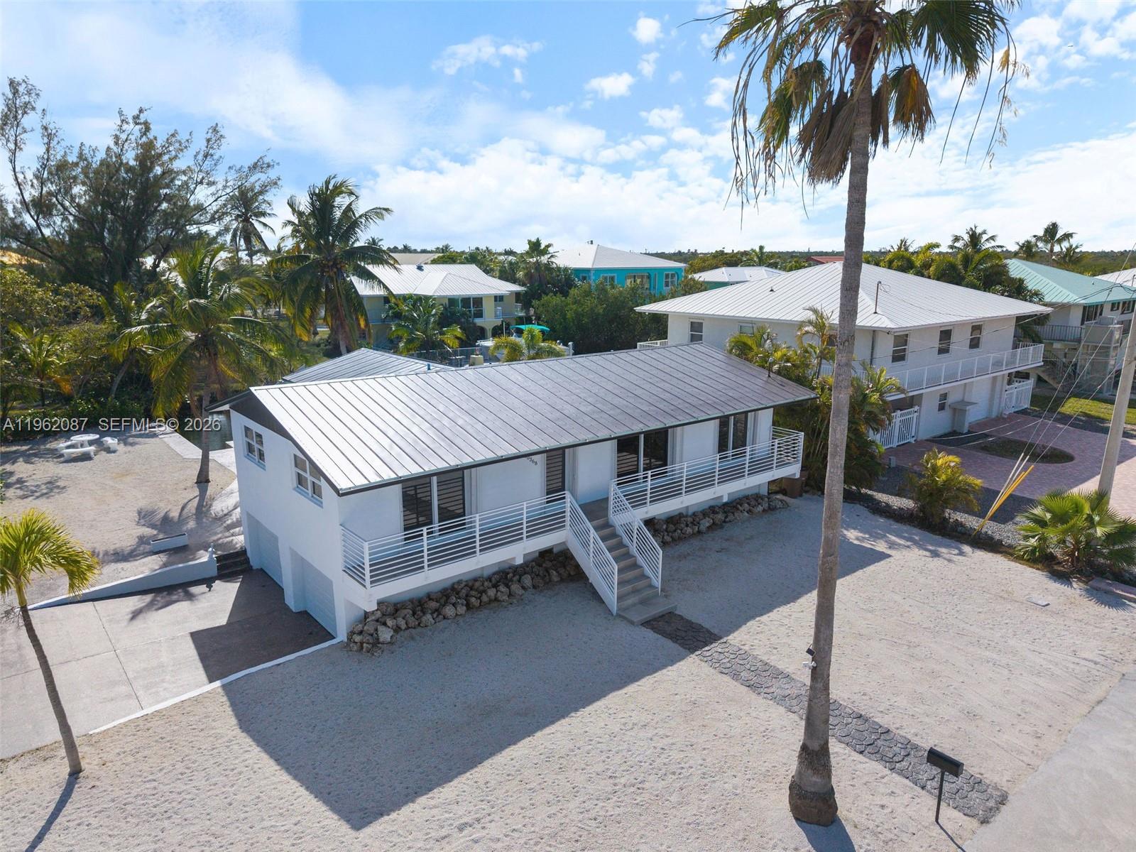 An elevated white house with a metal roof stands on a sandy lot — 30368 Killdeer Ln, Big Pine FL 33043, BIG PINE, FL