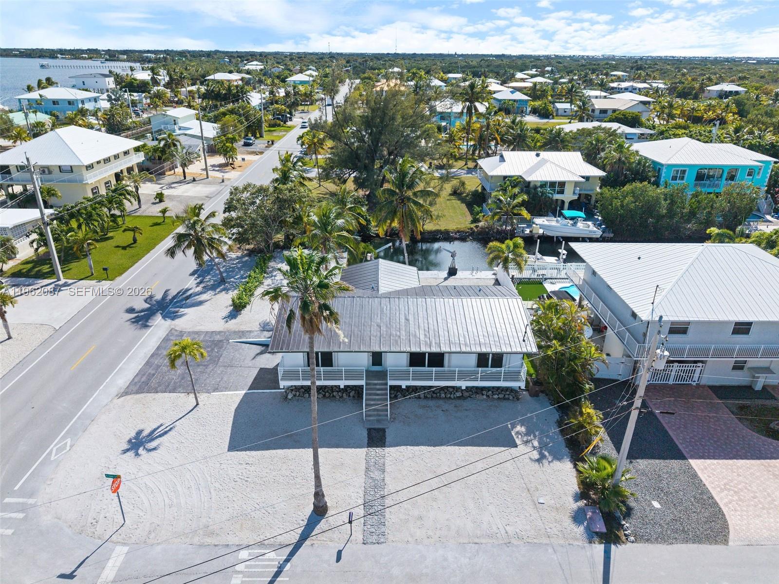 An aerial view shows a white house with a metal roof near a canal — 30368 Killdeer Ln, Big Pine FL 33043, BIG PINE, FL