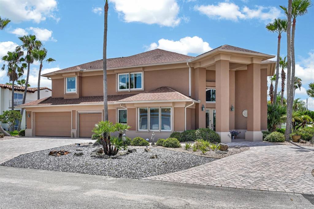 A two-story tan house with a paved driveway, palm trees, and a gravel front yard — 621 RIVER VIEW ROAD, FLAGLER BEACH, FL