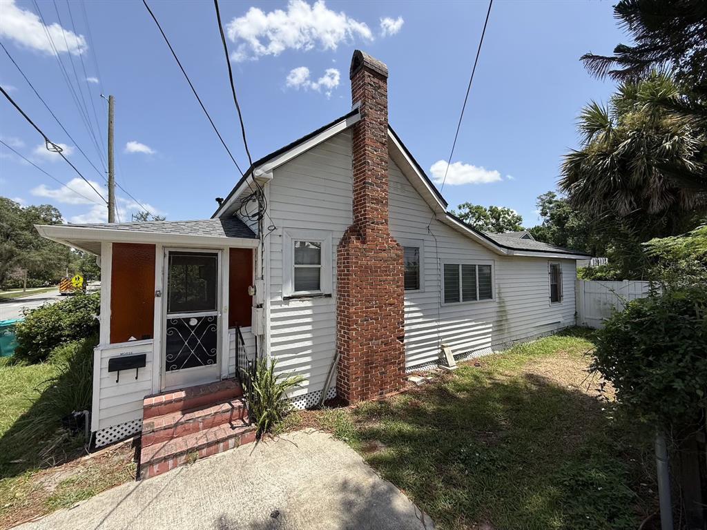A white house with a screened-in front porch stands on a grassy lot with trees — 1101 N HAMPTON AVENUE, ORLANDO, FL