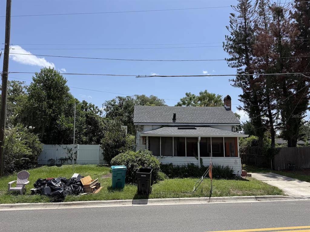 A white house with a screened-in front porch and a brick chimney stands near a driveway — 1101 N HAMPTON AVENUE, ORLANDO, FL