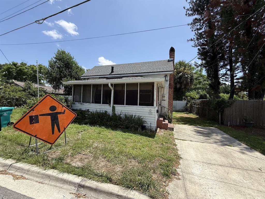 A white house with a brick chimney and a small front porch under a blue sky — 1101 N HAMPTON AVENUE, ORLANDO, FL
