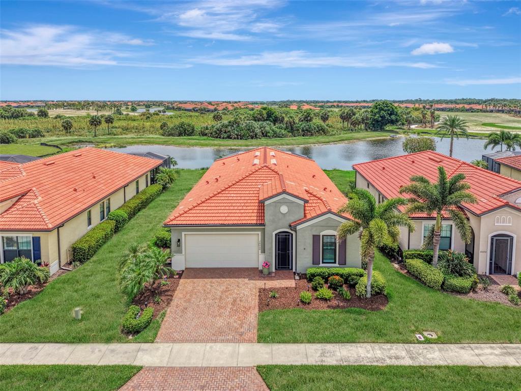 An aerial view of a single-story house with a red tile roof and brick driveway — 24268 GALLBERRY DRIVE, VENICE, FL