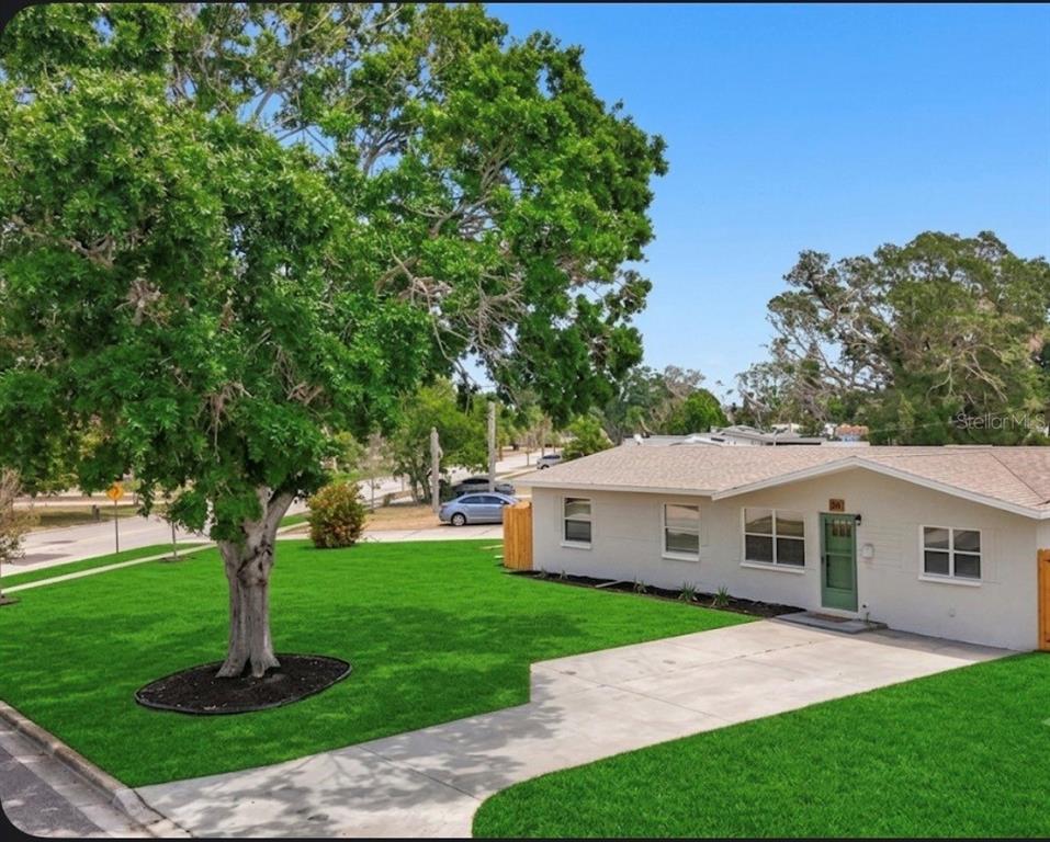 The exterior of a house features a green screen door, a white facade, and windows — 200 LEWIS BOULEVARD SE, ST PETERSBURG, FL