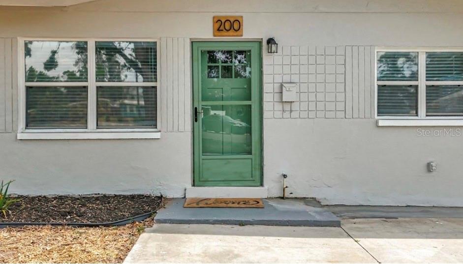 A kitchen with white cabinets and stainless steel appliances opens into a bright living area — 200 LEWIS BOULEVARD SE, ST PETERSBURG, FL