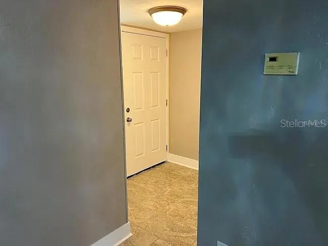 A hallway leads to a white door with a light fixture on the ceiling — 23104 SANDALWOOD DRIVE UNIT 104, WILDWOOD, FL