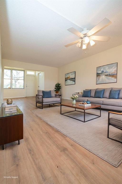 A living room features light wood flooring, a ceiling fan, and a gray sectional sofa — 4807 MARINE PARKWAY UNIT 103, NEW PORT RICHEY, FL