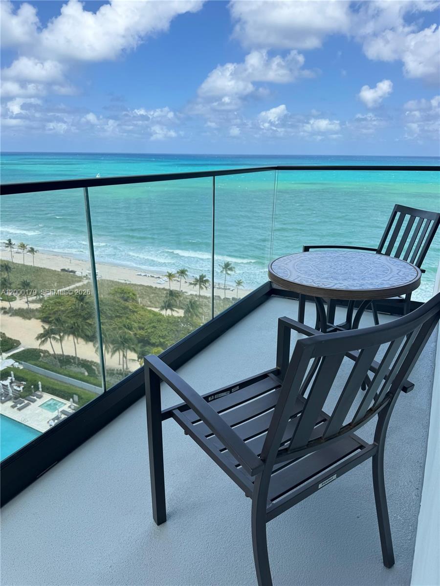 A balcony with a small table and two chairs overlooks the ocean and beach — 10185 collins # 20, Bal Harbour FL 33154, BAL HARBOUR, FL