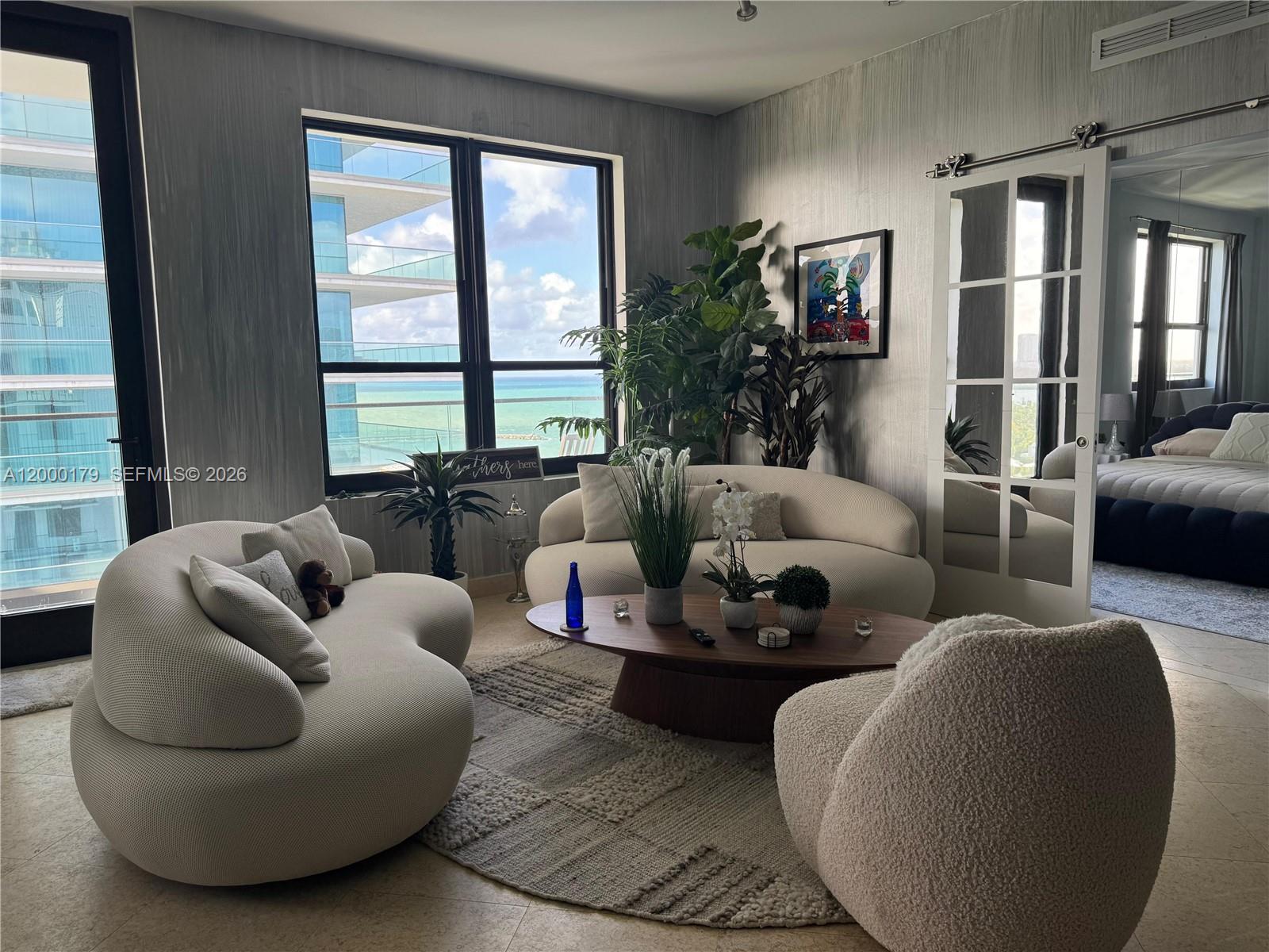 A living room features curved white sofas, a wooden coffee table, and ocean views — 10185 collins # 20, Bal Harbour FL 33154, BAL HARBOUR, FL
