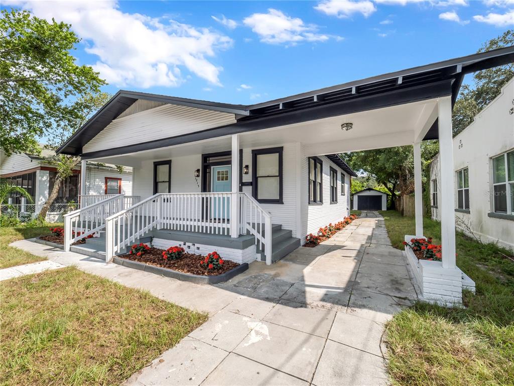 A white house with a front porch, carport, and a detached garage in the back — 1215 E 26TH AVENUE, TAMPA, FL