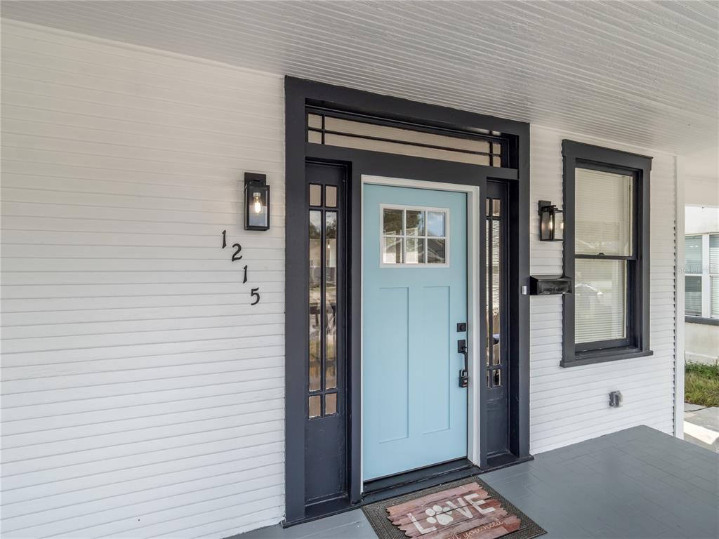A light blue front door with a transom window is centered on a white porch — 1215 E 26TH AVENUE, TAMPA, FL