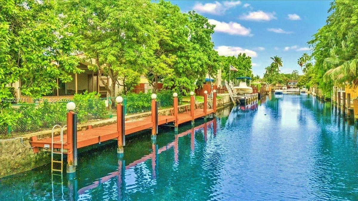 A wooden dock extends into a narrow canal lined with lush trees and residential properties — 2650 Scott St, Hollywood FL 33020, HOLLYWOOD, FL