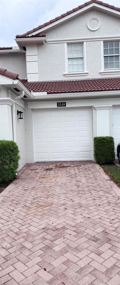 A white two-story house exterior features a single-car garage and a brick paver driveway — 2149 Wingate Bend, Wellington FL 33414, WELLINGTON, FL