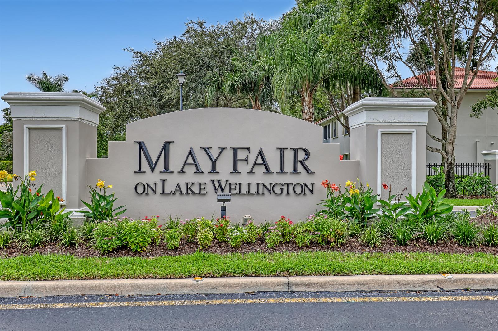 A beige monument sign for Mayfair on Lake Wellington stands behind a landscaped garden bed — 2149 Wingate Bend, Wellington FL 33414, WELLINGTON, FL