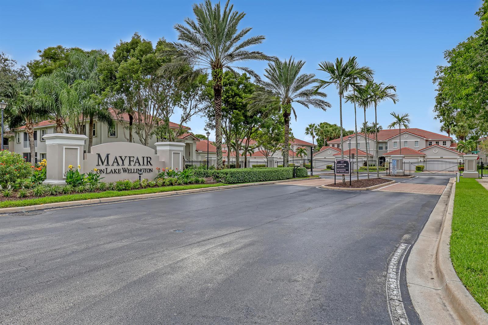 The gated entrance to Mayfair on Lake Wellington features a stone sign and palm trees — 2149 Wingate Bend, Wellington FL 33414, WELLINGTON, FL