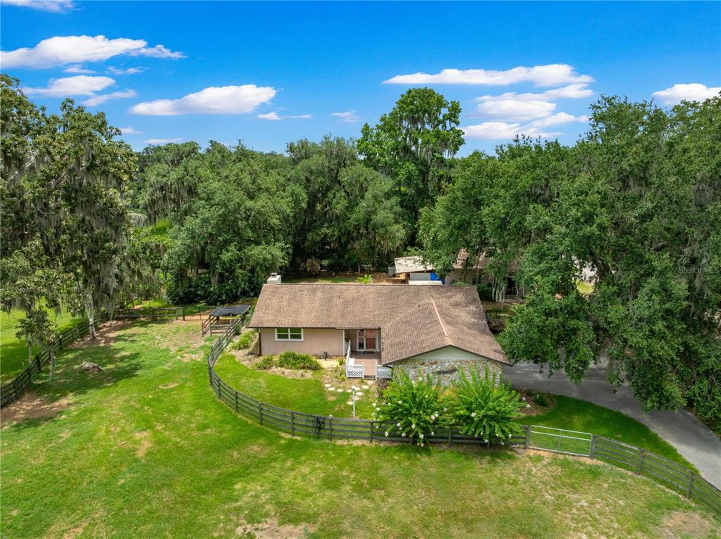 An aerial view of a single-story house with a stone facade and a fenced yard — 2645 SW 80TH STREET, OCALA, FL
