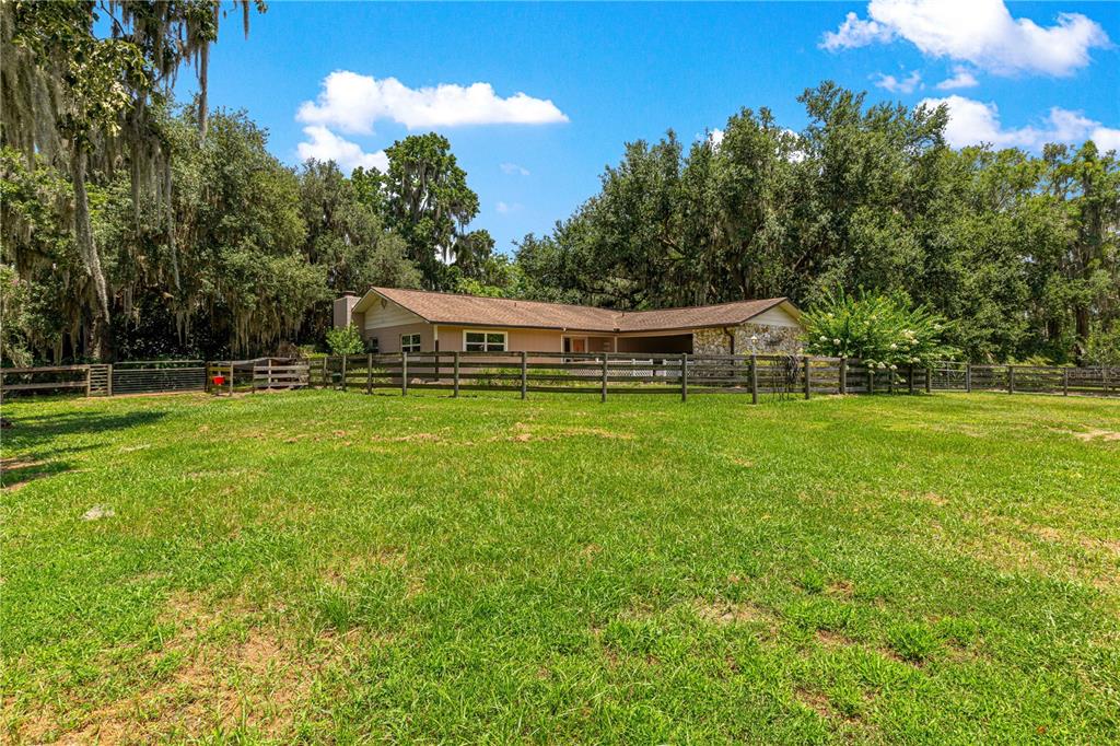 A single-story house with a stone facade sits behind a wooden fence in a yard — 2645 SW 80TH STREET, OCALA, FL
