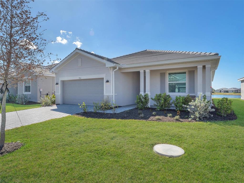 A single-story house with a gray garage, light-colored siding, and a paved driveway — 7961 LAKES EDGE LANE, PORT CHARLOTTE, FL