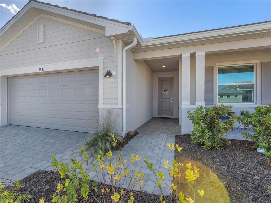 A single-story house exterior features a gray garage, a paved walkway, and a front entrance — 7961 LAKES EDGE LANE, PORT CHARLOTTE, FL
