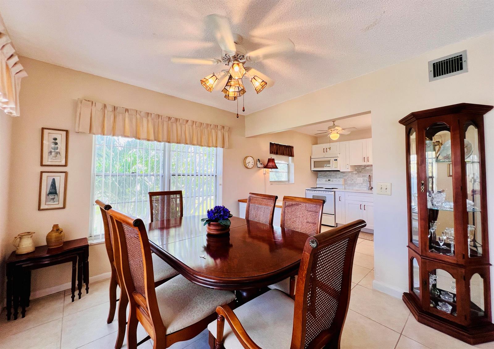 A dining room with a wooden table, chairs, and a china cabinet near a kitchen — 314 Wellington D, West Palm Beach FL 33417, WEST PALM BEACH, FL