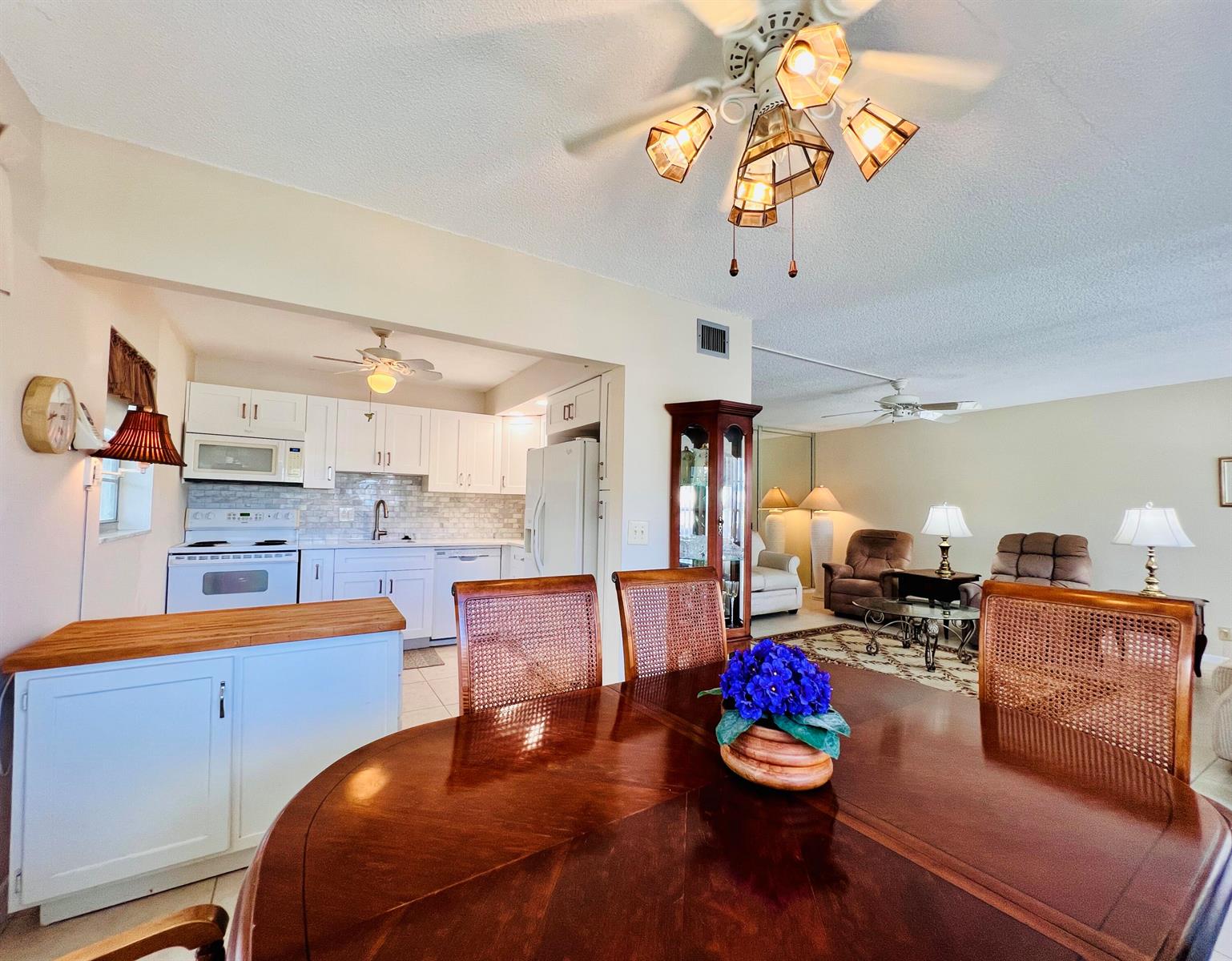 A dining room with a round wooden table overlooks an adjacent kitchen and living area — 314 Wellington D, West Palm Beach FL 33417, WEST PALM BEACH, FL