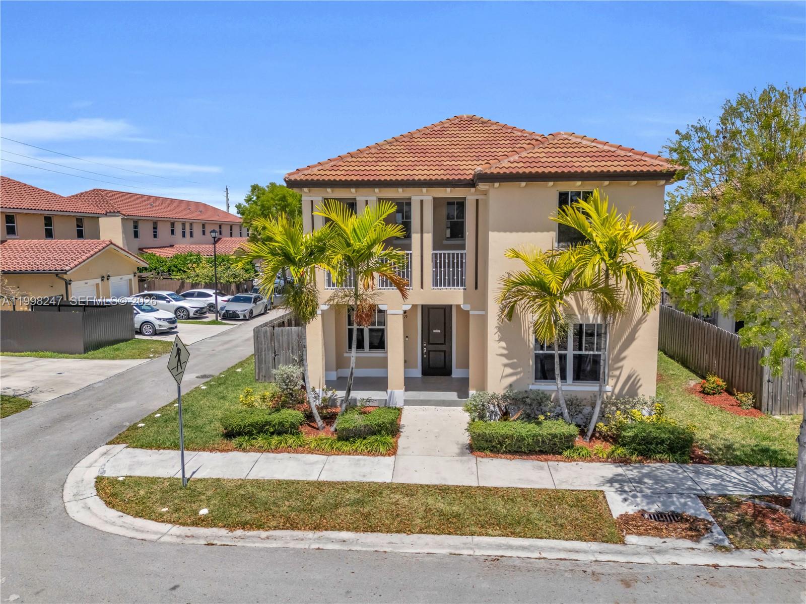 A two-story tan house with a tiled roof features a front balcony and palm trees — 11669 SW 247th St, Homestead FL 33032, HOMESTEAD, FL