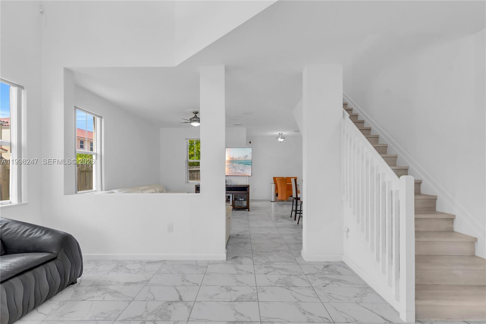 A bright living area features white tile floors, a staircase, and a partial wall divider — 11669 SW 247th St, Homestead FL 33032, HOMESTEAD, FL