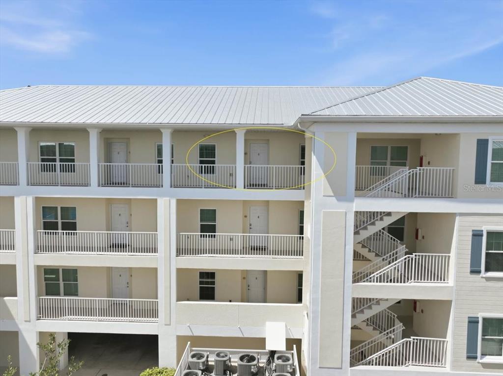 An exterior view of a multi-story apartment building with balconies and a metal roof — 8411 PLACIDA ROAD UNIT 407, PLACIDA, FL