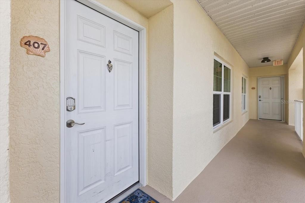 A kitchen with wood cabinets and granite countertops overlooks an entryway with tile flooring — 8411 PLACIDA ROAD UNIT 407, PLACIDA, FL