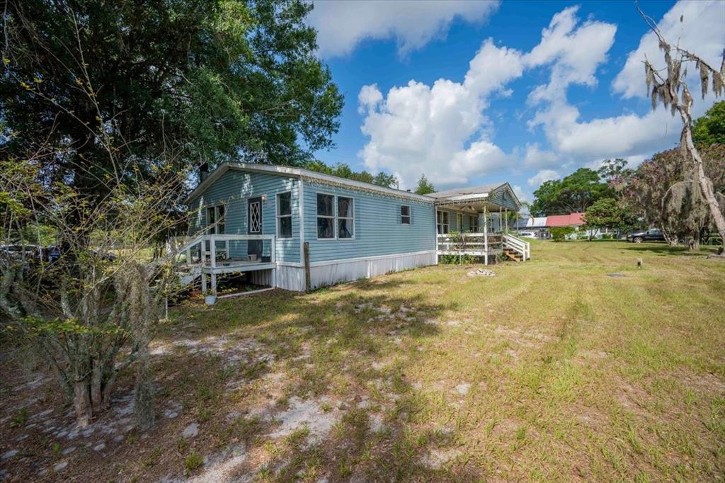A light blue manufactured home with a wooden deck stands on a grassy lot — 2210 D R BRYANT RD, LAKELAND, FL