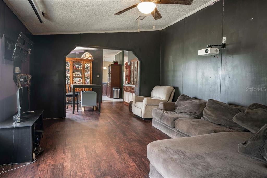 A living room features dark walls, wood-look flooring, a sectional sofa, and a ceiling fan — 2210 D R BRYANT RD, LAKELAND, FL