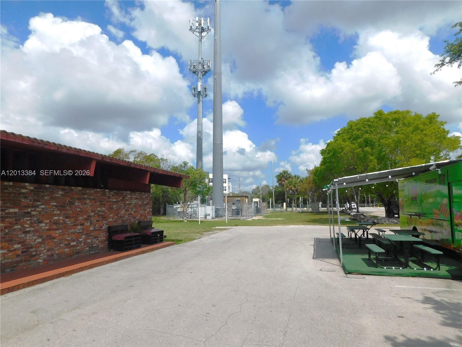 An outdoor area features a brick building, a food truck, and tall communication towers — 27230 S Dixie Hwy, Homestead FL 33032, HOMESTEAD, FL