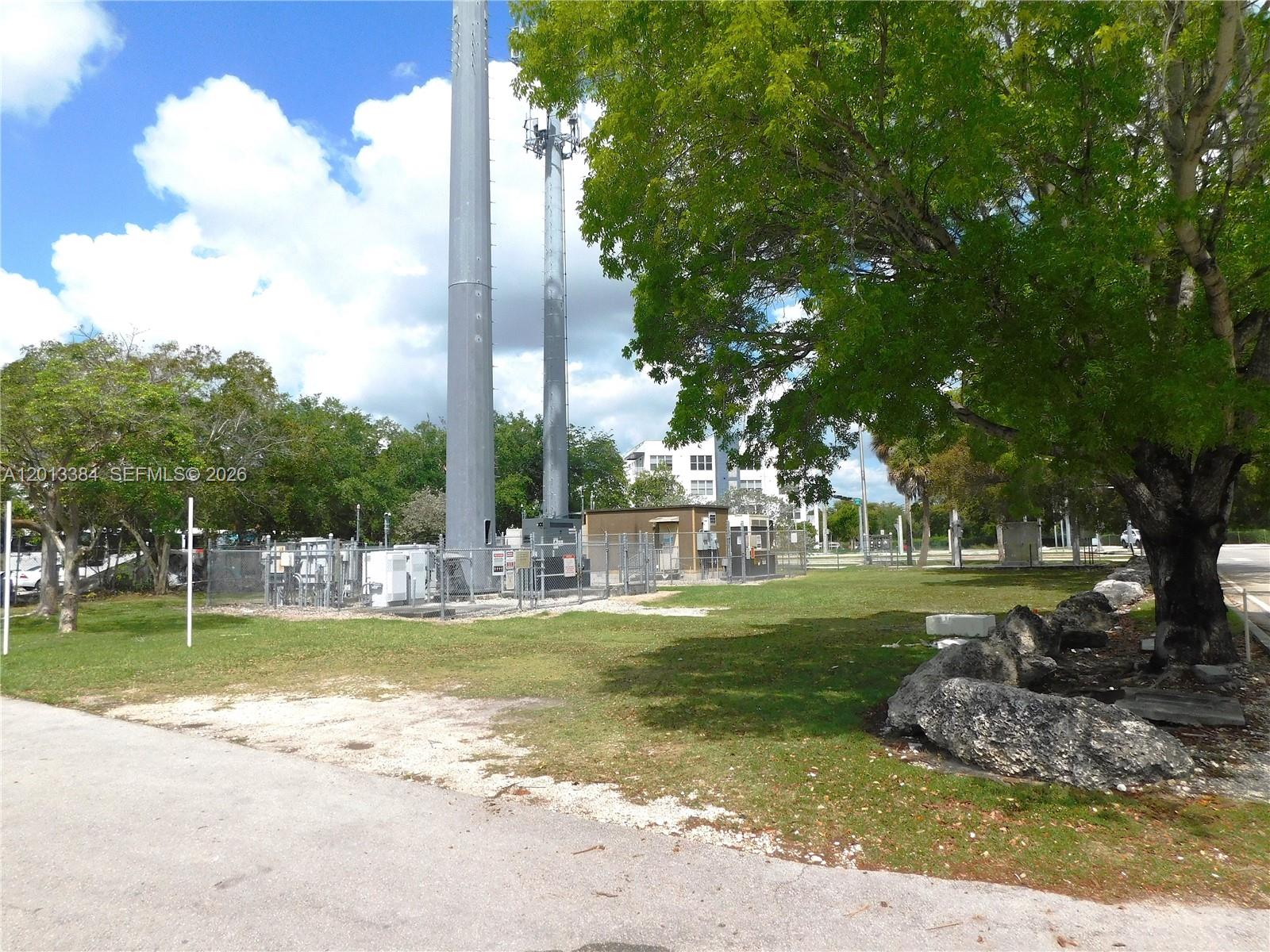 Two tall communication towers stand in a grassy lot next to a fenced equipment area — 27230 S Dixie Hwy, Homestead FL 33032, HOMESTEAD, FL