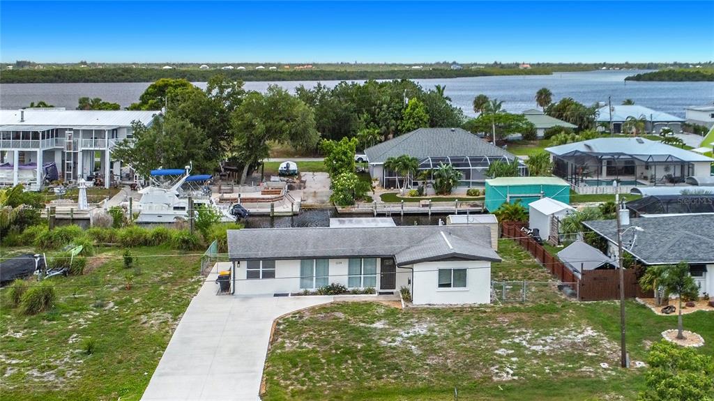 An aerial view shows a single-story house with a concrete driveway near a canal — 3234 DAYTONA DRIVE, PUNTA GORDA, FL