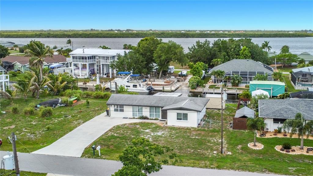 An aerial view shows a single-story house with a concrete driveway near a canal — 3234 DAYTONA DRIVE, PUNTA GORDA, FL