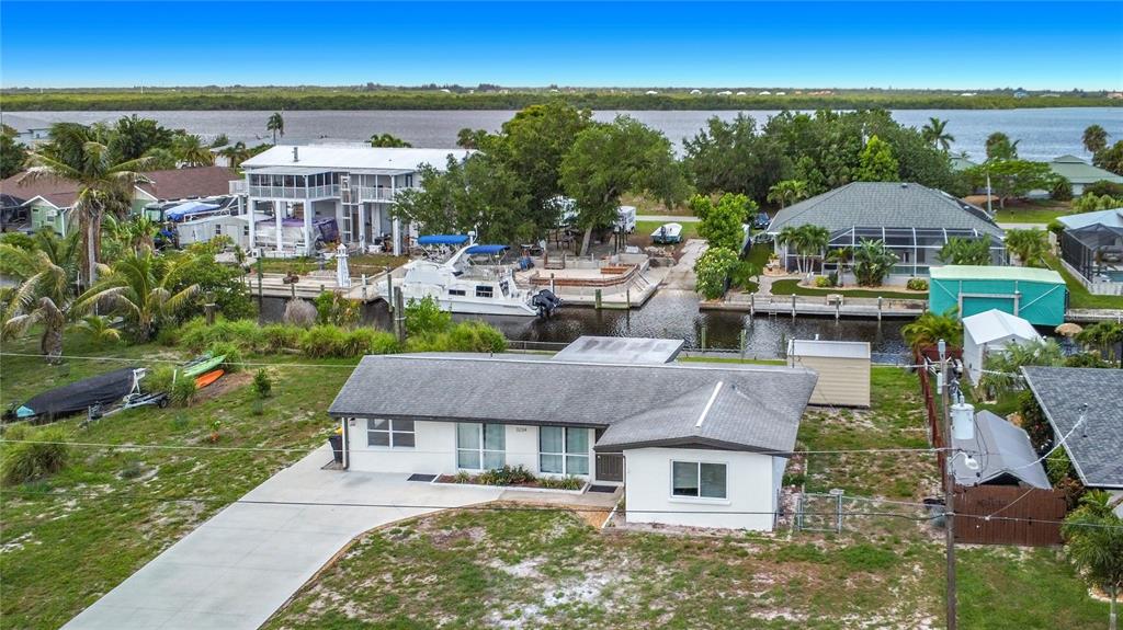An aerial view shows a single-story house with a concrete driveway near a canal — 3234 DAYTONA DRIVE, PUNTA GORDA, FL