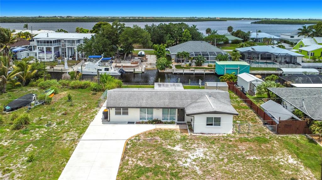 An aerial view shows a single-story house with a concrete driveway and a canal behind — 3234 DAYTONA DRIVE, PUNTA GORDA, FL