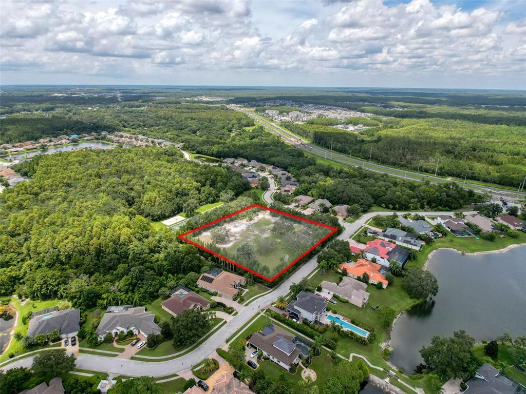 An aerial view shows a vacant, rectangular residential lot outlined in red within a suburban neighborhood — 15438/15440 AZRA DR, ODESSA, FL