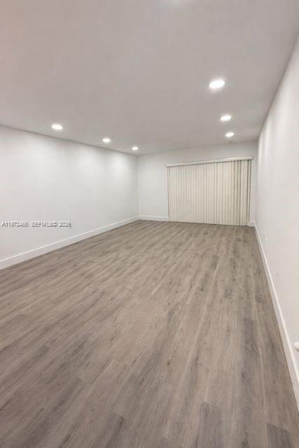 An empty room with white walls, recessed lighting, and light gray wood-look flooring — 1555 W 44th Pl # 247, Hialeah FL 33012, HIALEAH, FL