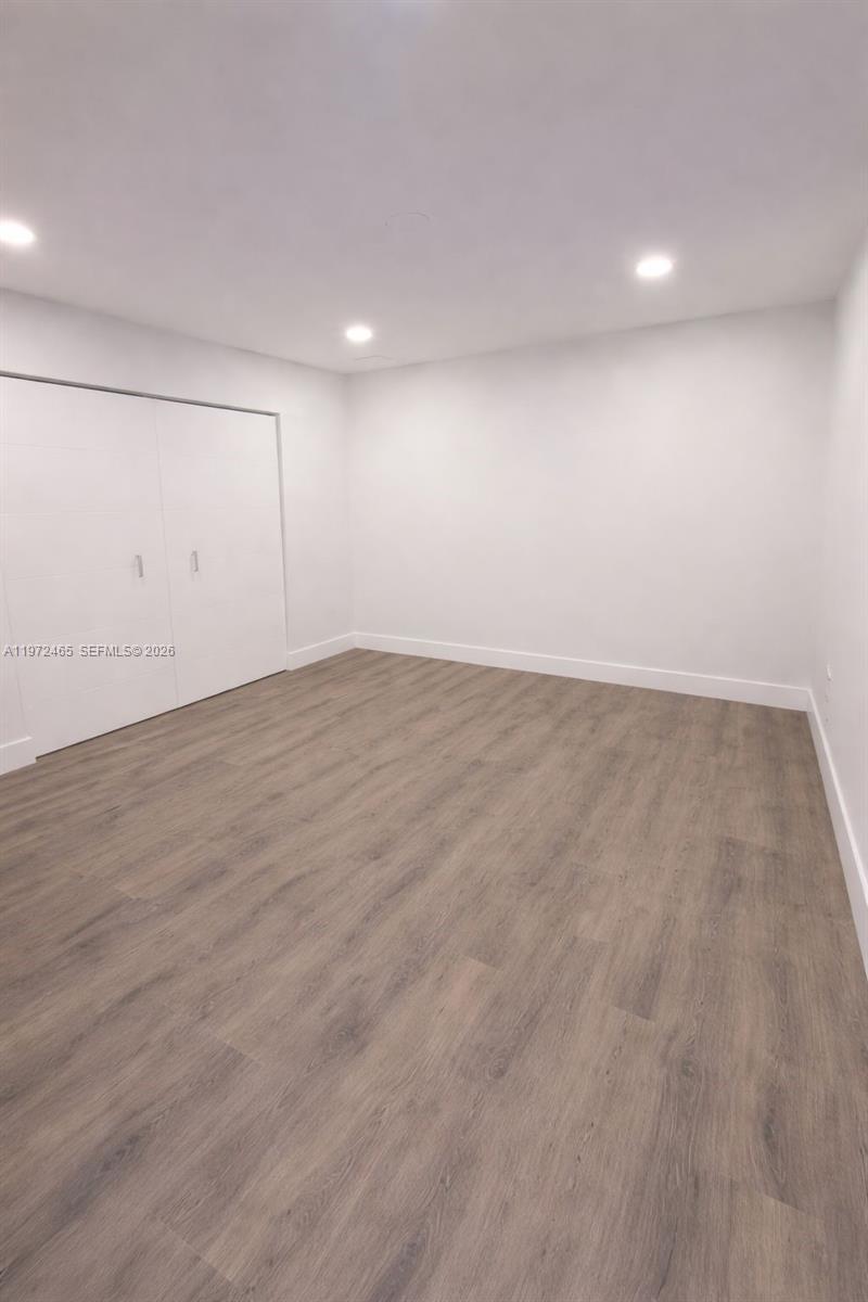 An empty room features white walls, recessed lighting, and light wood-look flooring — 1555 W 44th Pl # 247, Hialeah FL 33012, HIALEAH, FL