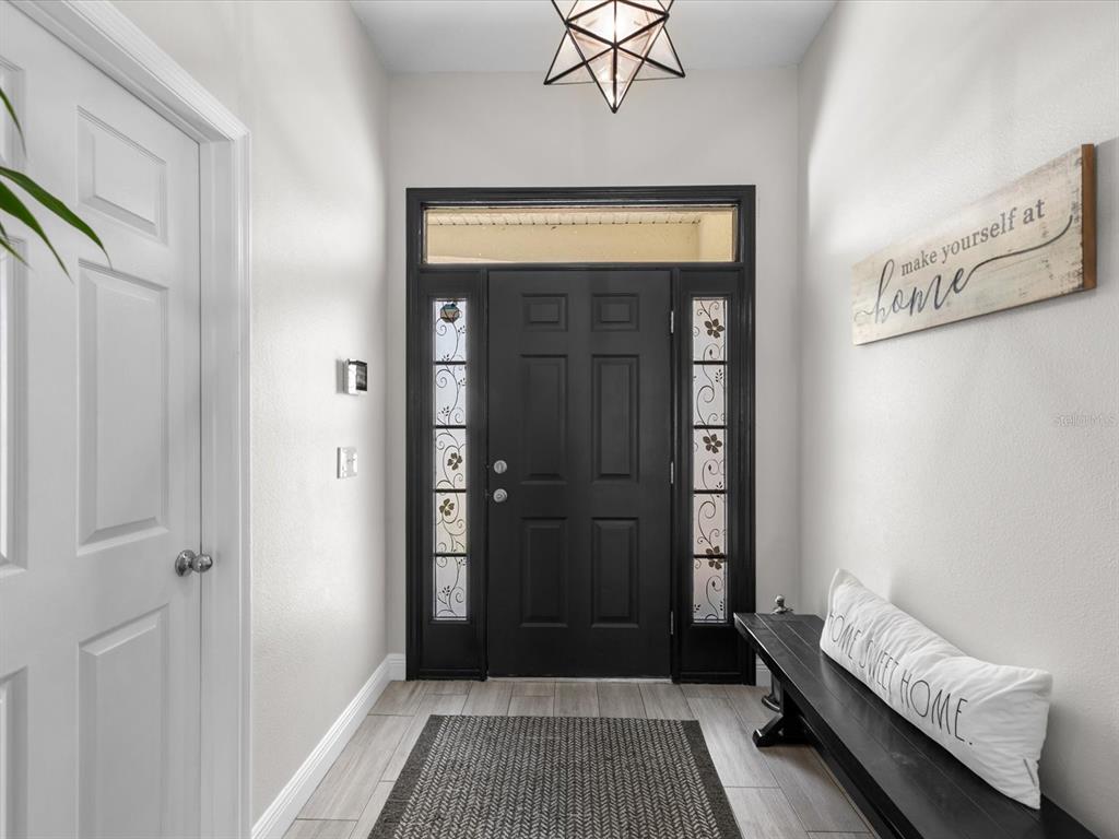 An entryway features a black front door with sidelights, a bench, and a geometric light — 4411 W OKLAHOMA AVENUE, TAMPA, FL