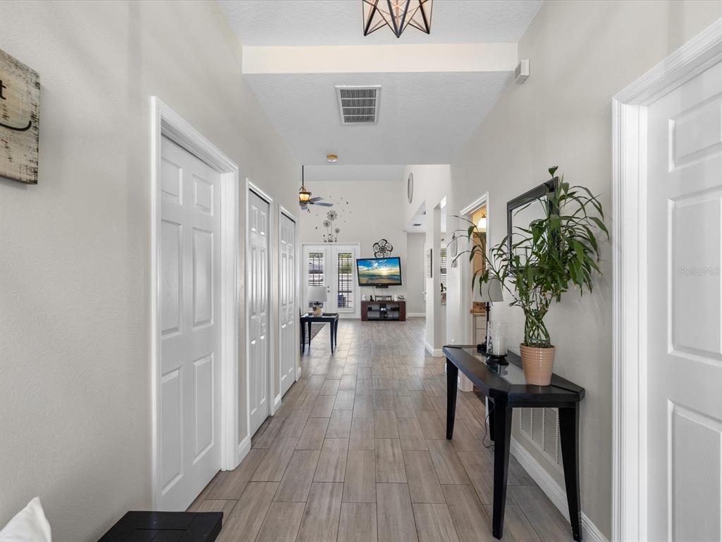 A bright hallway with light wood-look tile flooring leads toward an open living area — 4411 W OKLAHOMA AVENUE, TAMPA, FL
