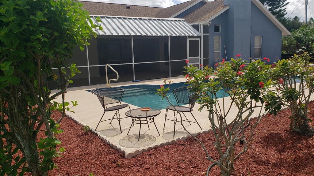 A backyard patio features a swimming pool, metal furniture, and a screened-in porch area — 7223 25TH DRIVE W, BRADENTON, FL