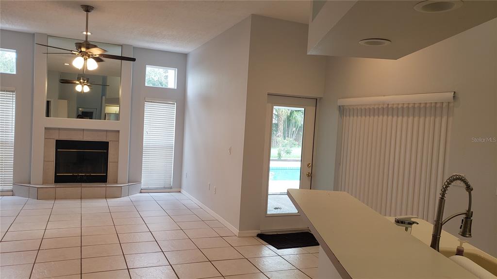 A living room with tile floors, a fireplace, a ceiling fan, and a sliding glass door — 7223 25TH DRIVE W, BRADENTON, FL