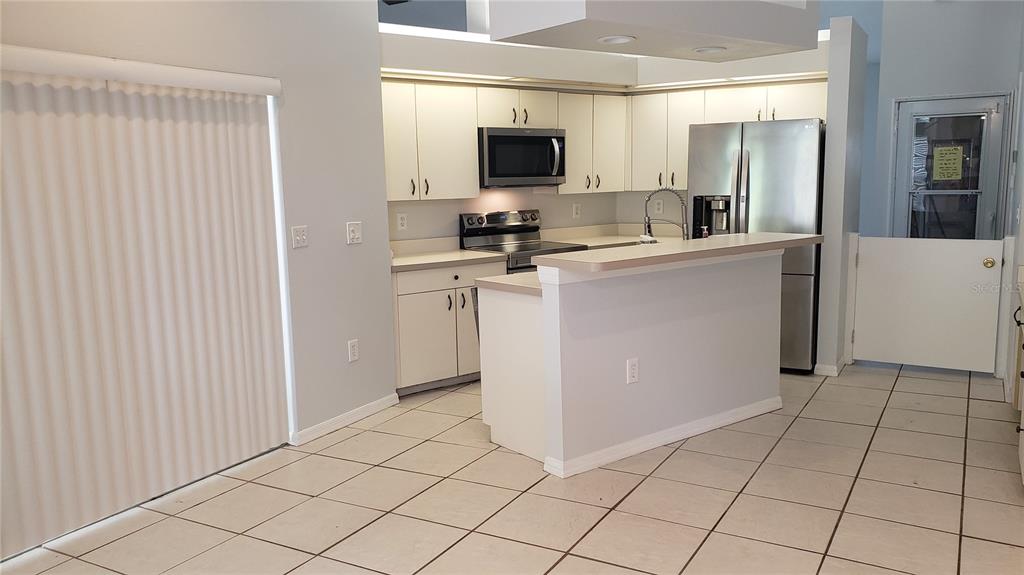 A kitchen with white cabinets, stainless steel appliances, a breakfast bar, and tiled flooring — 7223 25TH DRIVE W, BRADENTON, FL
