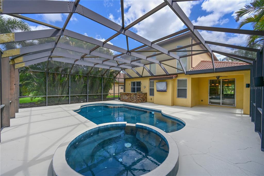 A screened-in patio features a swimming pool, a raised spa, and an outdoor bar area — 210 WINDING RIVER TRAIL, BRADENTON, FL