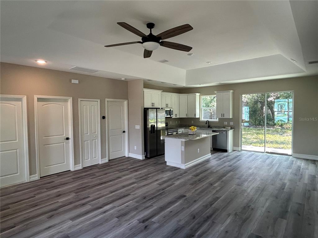 An open-concept kitchen and living area features white cabinetry, a center island, and wood-look flooring — 1176 EIGHTH STREET, ORANGE CITY, FL