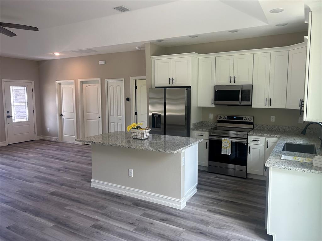 A kitchen with white cabinets, granite countertops, stainless steel appliances, and a central island — 1176 EIGHTH STREET, ORANGE CITY, FL